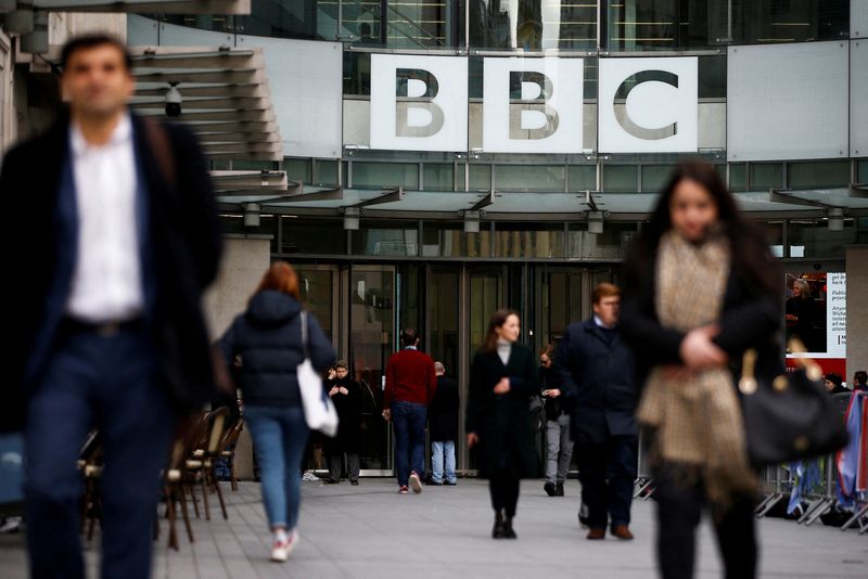 FILE PHOTO: Pedestrians walk past a BBC logo at Broadcasting House, as the corporation announced it will cut around 450 jobs from its news division, in London