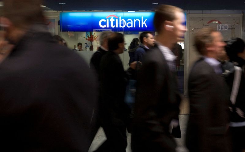 FILE PHOTO: People walk past a Citibank branch during the lunchtime rush in London's financial district of Canary Wharf