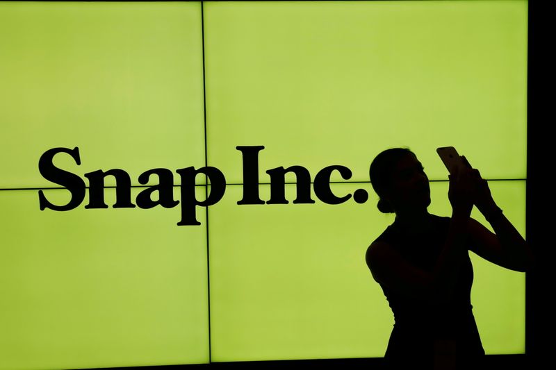 FILE PHOTO: FILE PHOTO: A woman stands in front of the logo of Snap Inc on the floor of the New York Stock Exchange (NYSE) in New York City