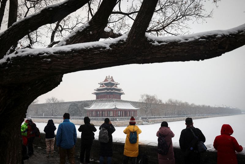 People take pictures of the Forbidden City after an overnight snowfall as the spread of COVID-19 continues, in Beijing