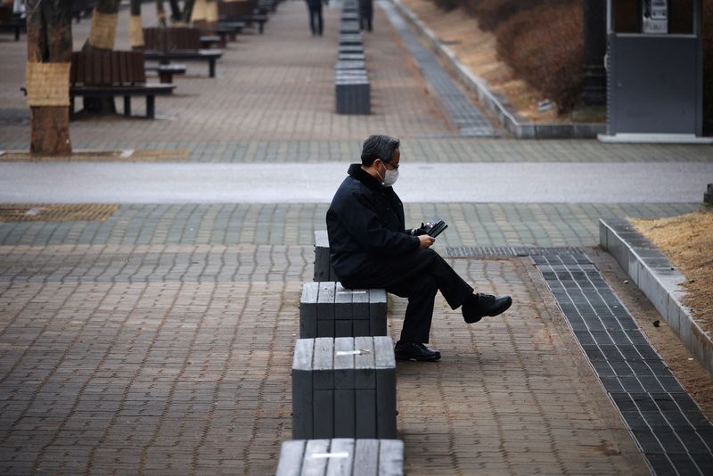 A man wearing a mask to prevent contracting the coronavirus disease (COVID-19) rests at an empty park in Seoul