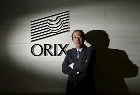 Orix Corp CEO Inoue poses in front of the company logo after an interview with Reuters in Tokyo