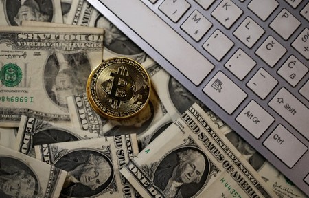 A bitcoin (virtual currency) coin placed on Dollar banknotes is seen in this illustration picture