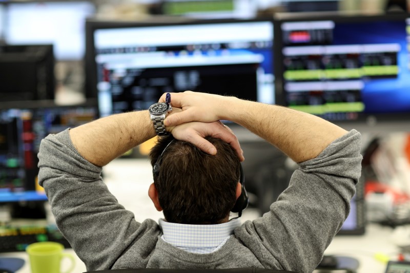 FILE PHOTO: A broker looks at financial information on computer screens on the IG Index trading floor