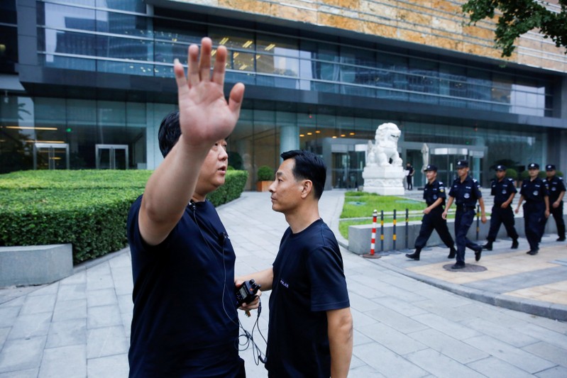 FILE PHOTO: A police officer gestures at the photographer as security patrol outside the headquarters of China's banking regulator in Beijing