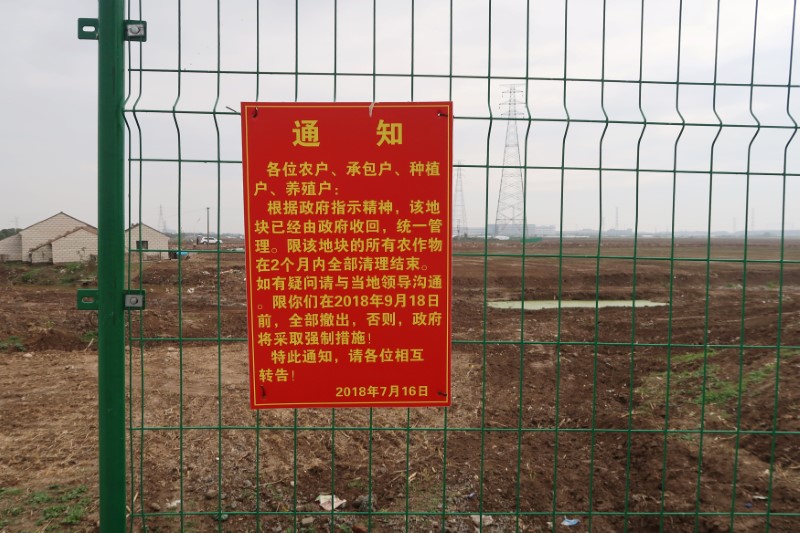 Government announcement of a land request is seen on a fence on the land secured by Tesla for its Gigafactory in Shanghai