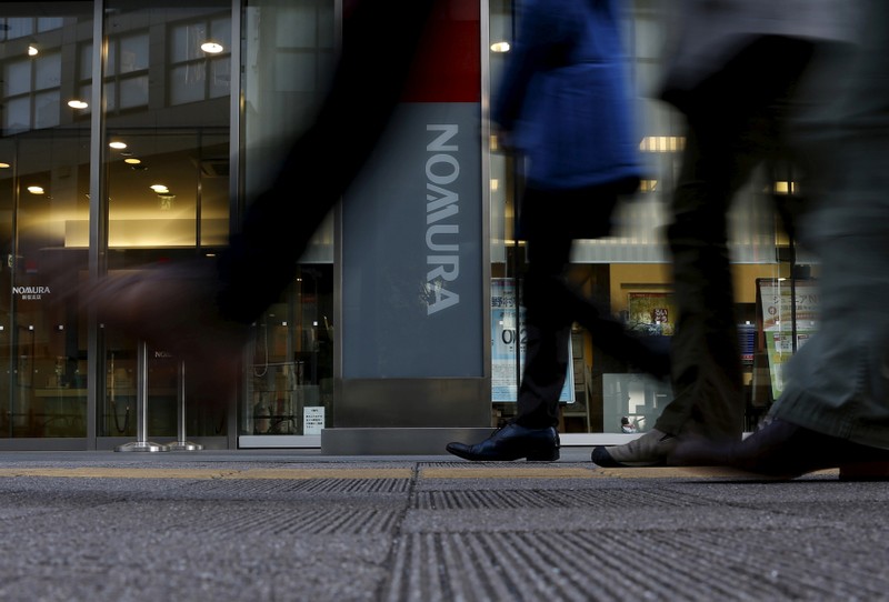 FILE PHOTO - Pedestrians walk past a signboard of Nomura Securities outside its branch in Tokyo