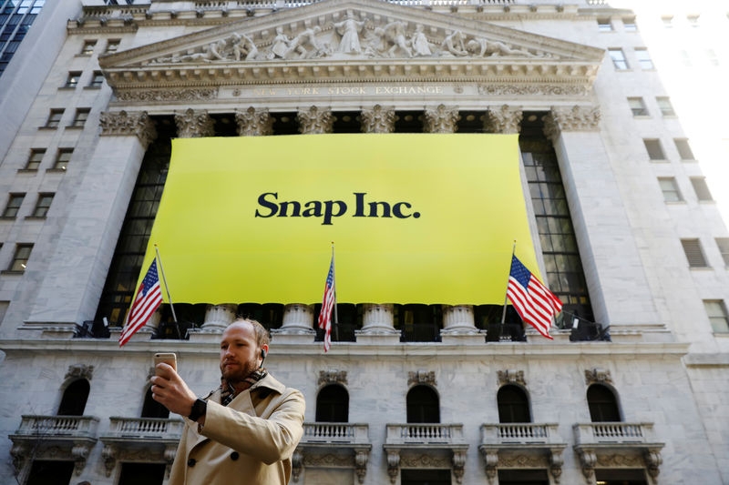 FILE PHOTO: A man takes a photograph of the front of the New York Stock Exchange (NYSE) with a Snap Inc. logo hung on the front of it shortly before the company's IPO in New York