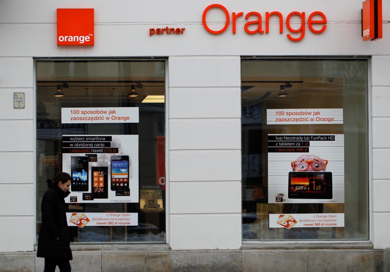 FILE PHOTO: A woman passes in front of an Orange store in Warsaw