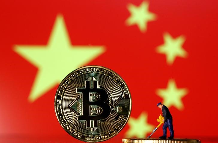 Picture illustration of a small toy figurine and representations of the Bitcoin virtual currency displayed in front of an image of China's flag