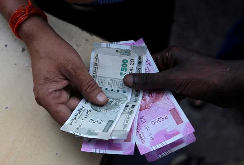 FILE PHOTO: A customer hands Indian currency notes to an attendant at a fuel station in Mumbai