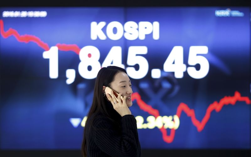 FILE PHOTO: Woman walks past electronic board KOSPI at the Korea Exchange in Seoul