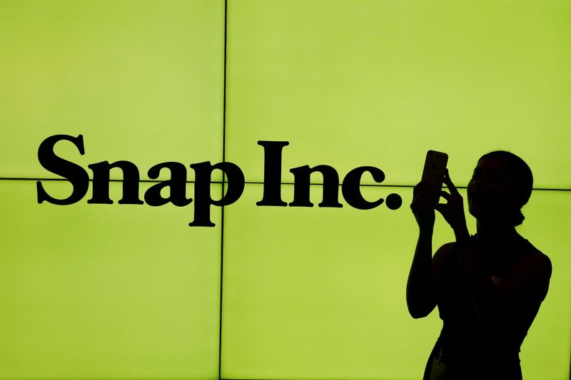 FILE PHOTO: FILE PHOTO: A woman stands in front of the logo of Snap Inc. on the floor of the New York Stock Exchange