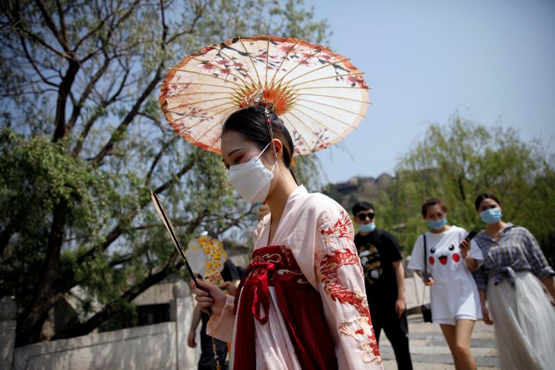 FILE PHOTO: A woman wearing face mask and traditional Chinese clothing visits Gubei Water Town on the first day of the five-day Labour Day holiday, following the coronavirus disease (COVID-19) outbreak, on the outskirts of Beijing