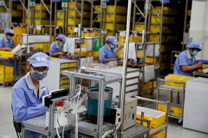 FILE PHOTO: Employees wearing face masks work at a factory of the component maker SMC during a government organised tour of its facility following the outbreak of the coronavirus disease (COVID-19), in Beijing