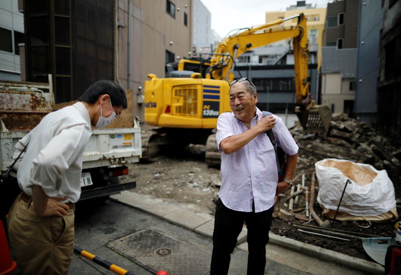 Fumiaki Ichiyama who managed Yonosuke that closed the business this spring, talks with a former neighbor in front of the site where his bar was located amid the coronavirus disease (COVID-19) outbreak, in Tokyo