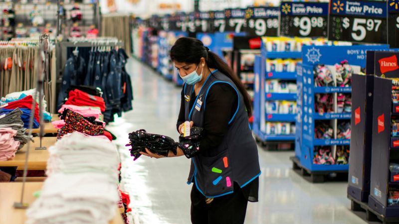 A worker is seen wearing a mask while organizing merchandise at a Walmart store, in North Brunswick, New Jersey