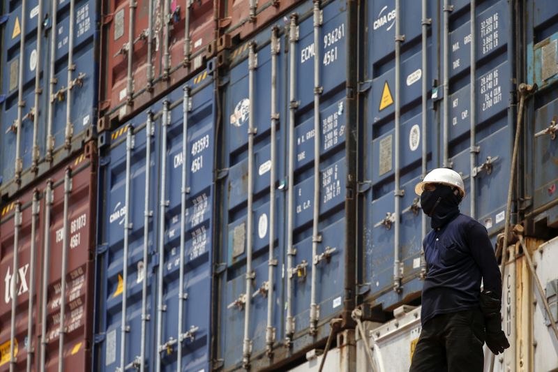 FILE PHOTO: A worker stands next to shipping containers on a ship at a port in Bangkok