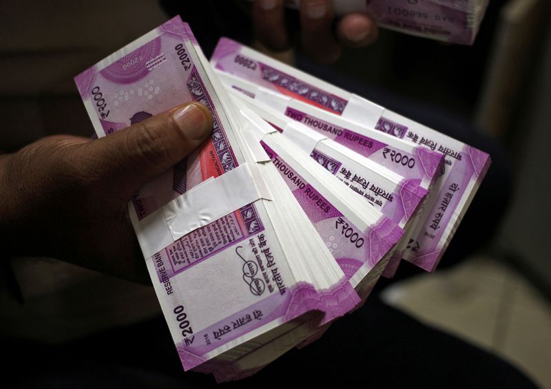 FILE PHOTO: A cashier displays the new 2000 Indian rupee banknotes inside a bank in Jammu