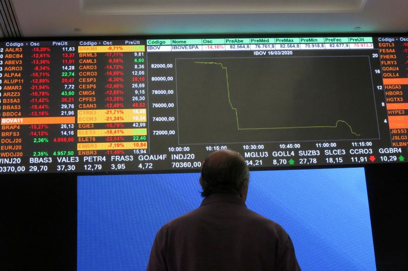 FILE PHOTO: A man stands in front of an electronic display at B3 Brazilian Stock Exchange after an automatic circuit breaker was triggered this morning, in Sao Paulo