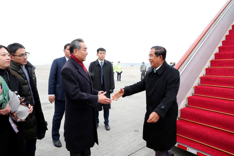 FILE PHOTO: Chinese State Councilor and Foreign Minister Wang Yi welcomes Cambodian Prime Minister Hun Sen as he arrives at the Beijing Capital International Airport