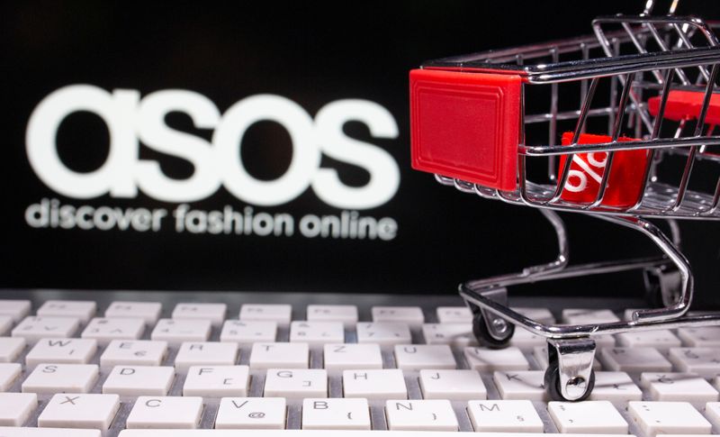 A keyboard and a shopping cart are seen in front of a displayed ASOS logo in this illustration picture