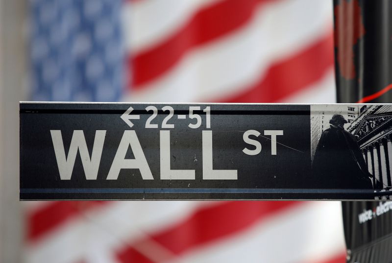 FILE PHOTO: A sign for Wall Street is seen with a giant American flag in the background across from the New York Stock Exchange