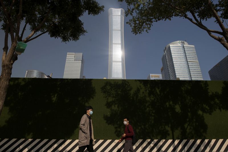 People walk past the skyline of the Central Business District (CBD) on the day that Chinese leaders elaborate on their 14th Five-Year plan in Beijing