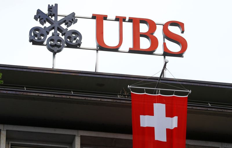Switzerland's national flag flies below a logo of Swiss bank UBS in Zurich