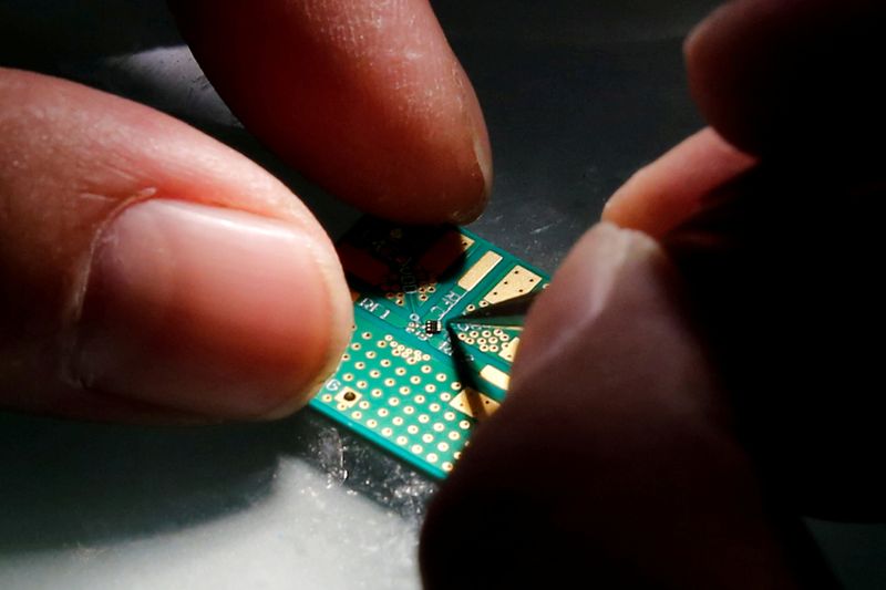 FILE PHOTO: A researcher plants a semiconductor on an interface board during a research work to design and develop a semiconductor product at Tsinghua Unigroup research centre in Beijing