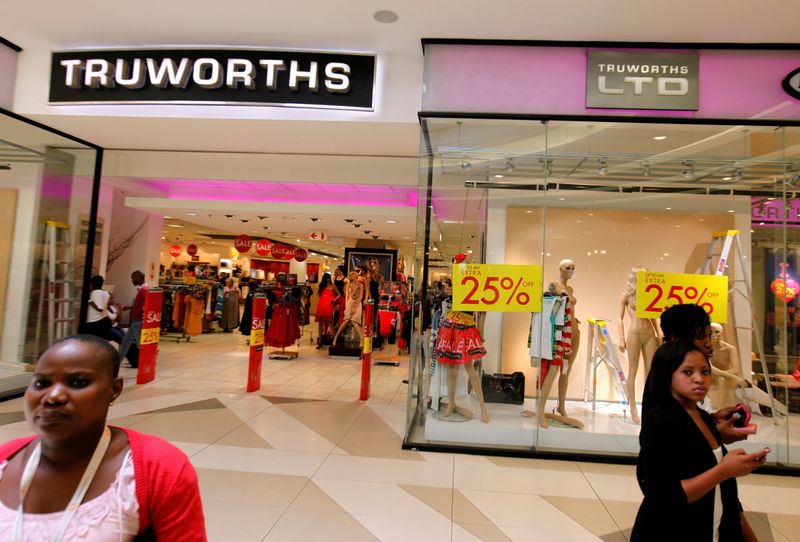 FILE PHOTO: Shoppers walk past a Truworths shop with Sale advertisements on its windows at the Sandton shopping mall in Johannesburg