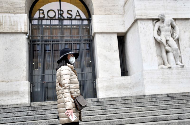 Una donna con una mascherina davanti alla Borsa di Milano