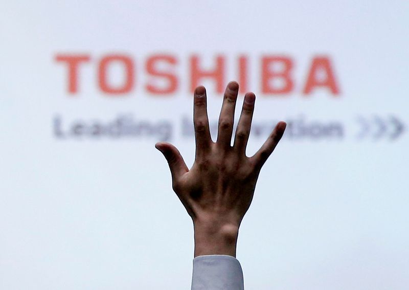 FILE PHOTO: A reporter raises his hand for a question during a news conference by Toshiba Corp CEO Satoshi Tsunakawa at the company headquarters in Tokyo