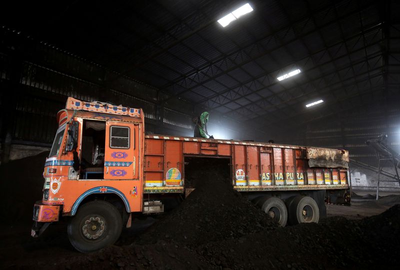 FILE PHOTO: Worker shovels coal in a supply truck at a yard on the outskirts of Ahmedabad