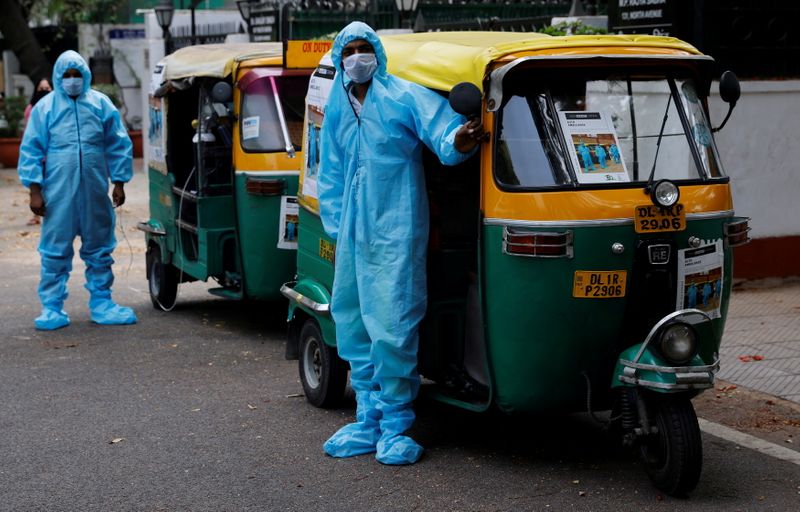 Drivers stand near auto rickshaw ambulances, prepared to transfer people suffering from COVID-19 and their relatives for free, in New Delhi