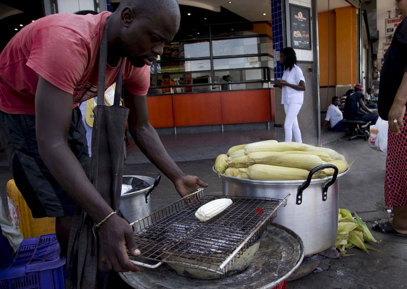 FILE PHOTO: A vendor sells maize cobs to a commuter in Durban