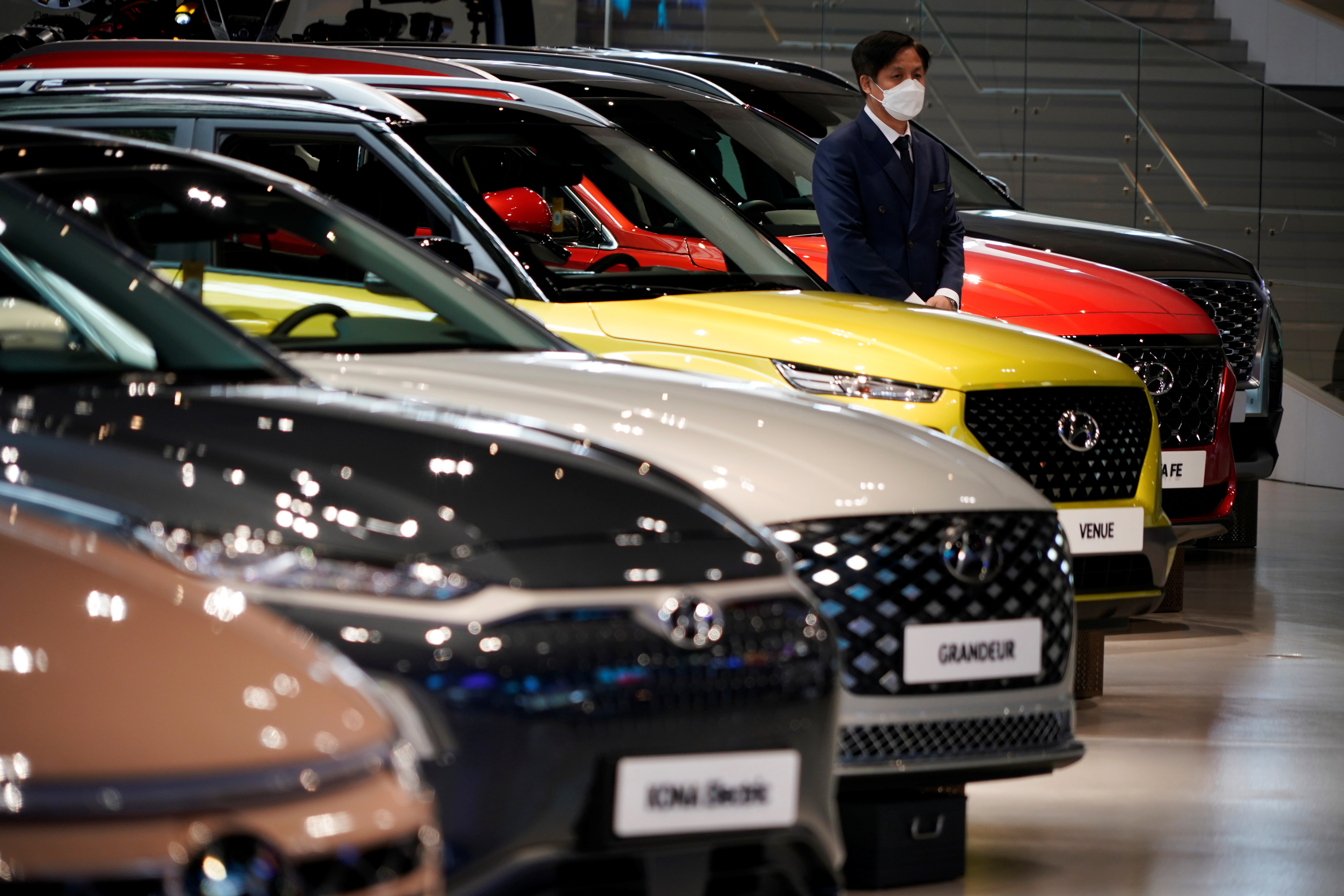 FILE PHOTO: An employee wearing a mask to prevent contracting the coronavirus disease (COVID-19) waits for custormers next to a Hyundai Motor's vehicle at Hyundai Motor Studio in Goyang