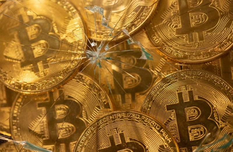 FILE PHOTO: Representations of virtual currency bitcoin are seen through broken glass in this illustration