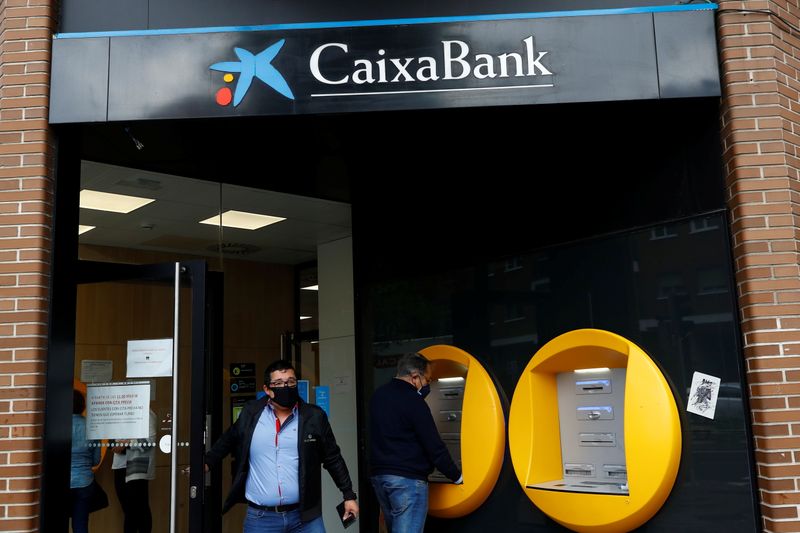 FILE PHOTO: A person walks out of a Caixabank's bank branch in Madrid