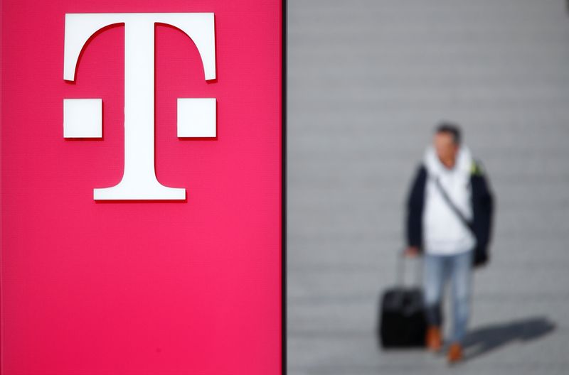 FILE PHOTO: A man walks past the logo of Deutsche Telekom AG at the headquarters of German telecommunications giant in Bonn