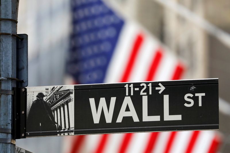 Un cartello stradale di  Wall Street davanti a una bandiera statunitense