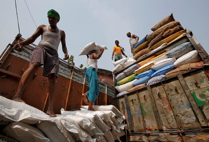 FILE PHOTO: A labourer carries a sack filled with sugar to load it onto a supply truck at a wholesale market in Kolkata, India