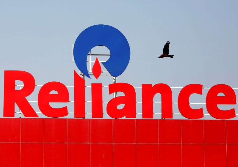 FILE PHOTO: A bird flies past a Reliance Industries logo installed on its mart in Ahmedabad
