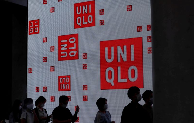 FILE PHOTO: People wearing masks stand in a queue to enter Uniqlo's newly launched shop in Tokyo