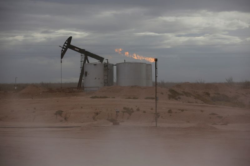 FILE PHOTO: Dust blows around a crude oil pump jack and flare burning excess gas at a drill pad in the Permian Basin in Loving County