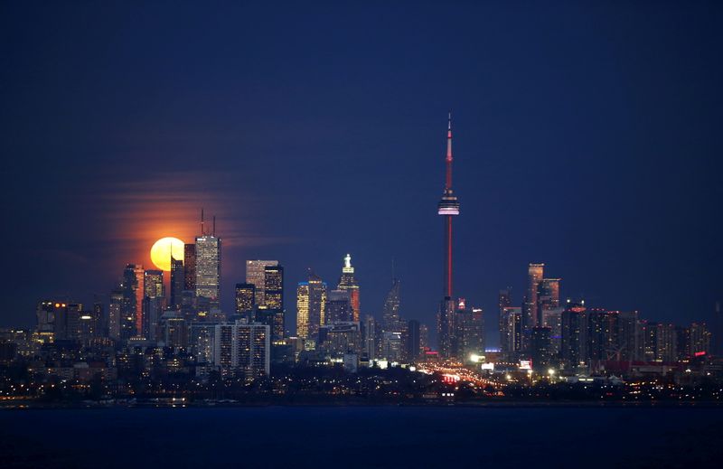 FILE PHOTO: The moon rises behind the skyline and financial district in Toronto