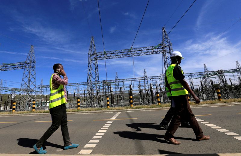 FILE PHOTO: Kenya Electricity Generating Company workers walk past the pylons of high-tension electricity power lines at the Olkaria II Geothermal power plant near the Rift Valley town of Naivasha