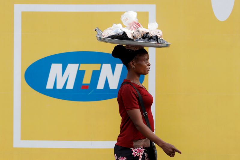 FILE PHOTO: A woman walks past an advertising posters for MTN telecommunication company along a street in Lagos