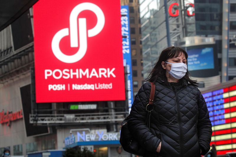 A woman walks through Times Square as a screen displays the company logo for Poshmark Inc. during it's IPO at the Nasdaq Market Site in Times Square in New York