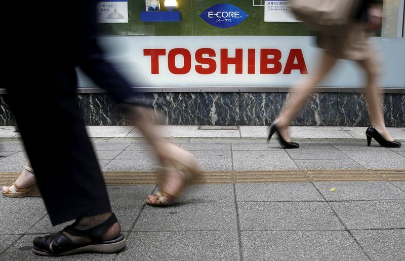 FILE PHOTO: Pedestrians walk past a logo of Toshiba Corp outside an electronics retailer in Tokyo